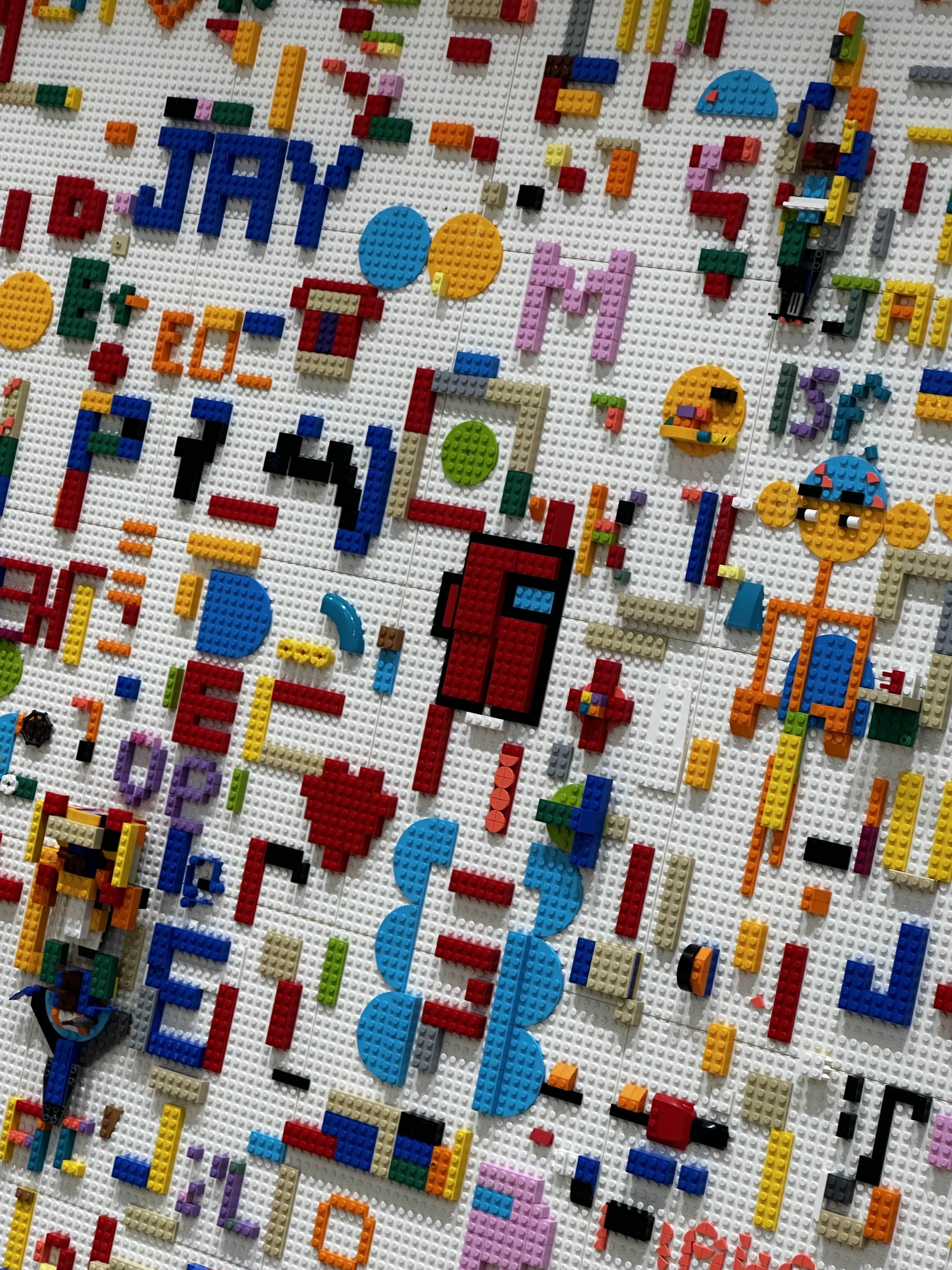 Picture of a lego brick wall with an among us crewmate made from lego